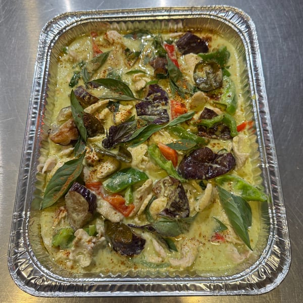 Thai green curry with chicken, eggplant, and basil in a foil takeout container.